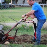 Dad and son tilling the soil